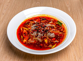 Sichuan Spicy boiled beef with red pepper, onion and sesame seeds served in bowl isolated on wooden table side view of hong kong food