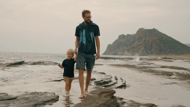 Smiling father and son walking sea beach wave seaside landscape tropical resort travel vacation