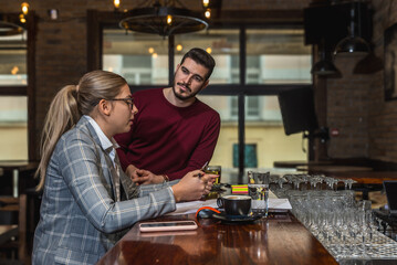 Owner and manager calculating daily earning and taxes in the cafeteria of coffee shop. Small business owner doing ordering of drinks and food for rustic restaurant.