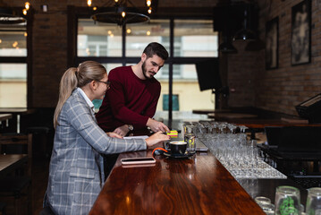 Owner and manager calculating daily earning and taxes in the cafeteria of coffee shop. Small business owner doing ordering of drinks and food for rustic restaurant.