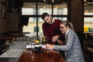 Owner and manager calculating daily earning and taxes in the cafeteria of coffee shop. Small...
