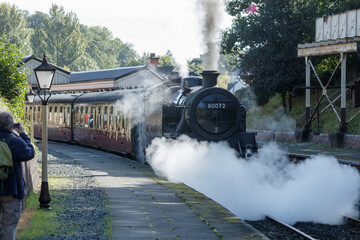 Steam train 80072 puffs smoke at a station.  Observer watches.