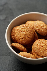 Freshly baked crunchy cookies in a white bowl on a dark surface perfect for snack time
