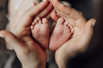 A baby's feet are being held by a parent. The baby's feet are small and white. The baby is likely a...