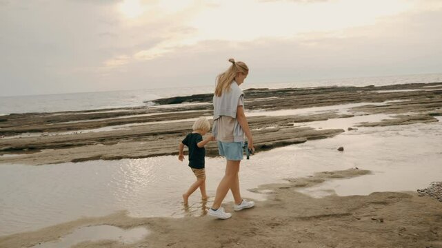Tourist family mother father and son kid walking sea beach coastline sunset sunrise slowmo