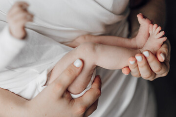 A woman is holding a baby's foot in her hand. The baby is wearing a white diaper