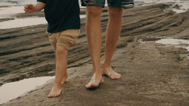 Father and son barefoot feet walking sea beach sand stone coastline enjoy travel vacation closeup