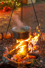 At night, a campfire with a pot for cooking