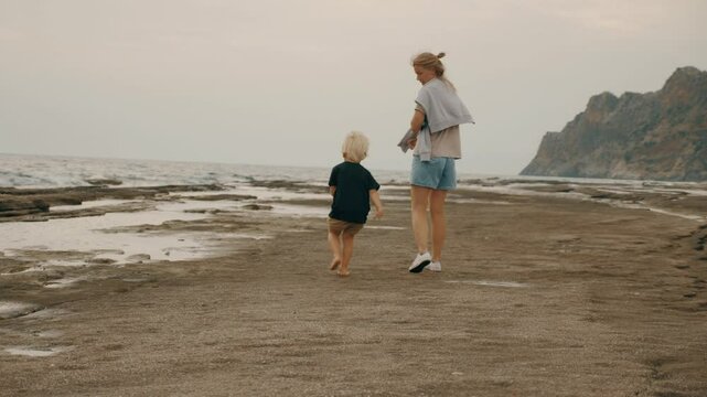 Resting mother and walking sea beach sand stone foamy wave landscape with dramatic sky slow motion