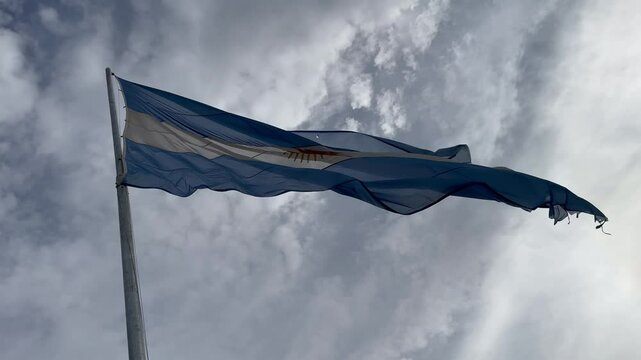 bandera argentina flameando sobre sol, cielo azul	
