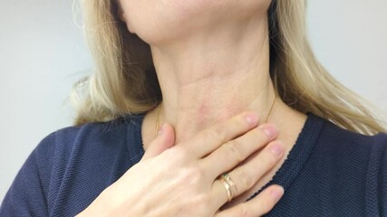 Blonde middle-aged blonde European woman looks closely at the skin on her neck. She is concerned about the appearance of wrinkles and signs of aging.