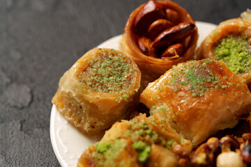 Traditional Middle Eastern sweets displayed on a white plate during a festive gathering at an outdoor market