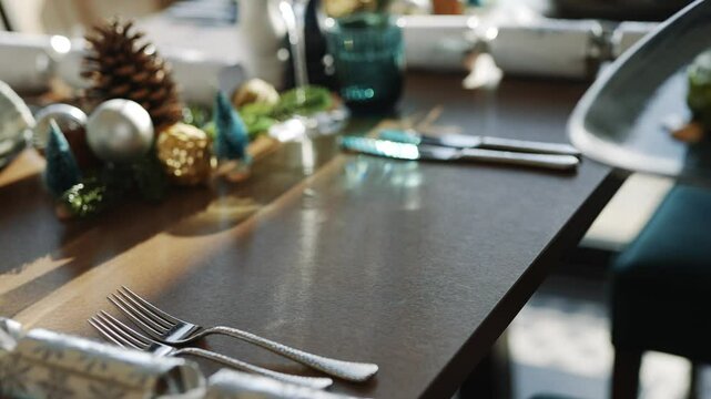 A table with a Christmas tree centerpiece and a blue tablecloth. The table is set with silverware and a fork