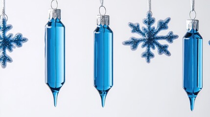 Blue glass Christmas ornaments and snowflakes hanging against a white background.