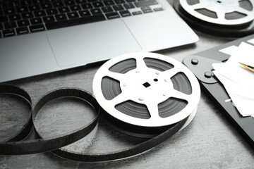 Film reels and laptop on grey textured table, closeup