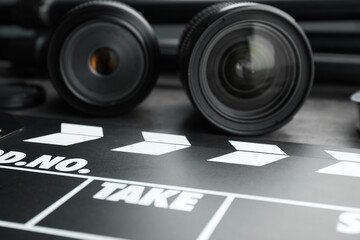 Movie clapper and camera lens on table, closeup