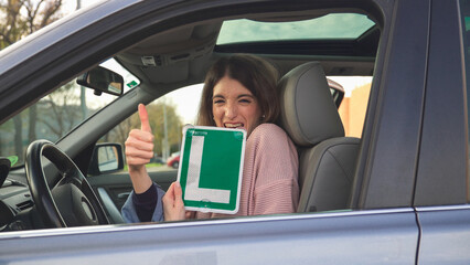 Young driver showing learner permit and giving thumbs up