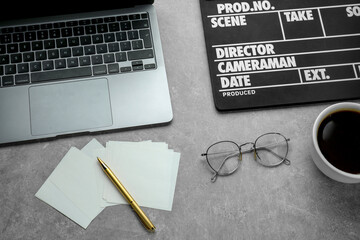 Flat lay composition with movie clapper and laptop on grey textured table