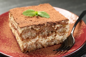 Delicious tiramisu with mint on dark table, closeup