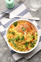 Tasty rice with vegetables and chicken served on grey table, top view