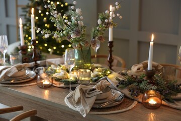 Christmas celebration. Festive table setting with dishware, glasses and decor in room