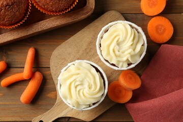 Tasty carrot muffins with fresh vegetables on wooden table, flat lay