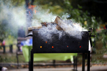 Brazier with wood in nature for cooking. outdoors on weekends or holidays, heavy smoke before...