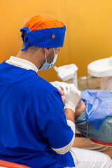 Dentist, seen from behind, performing dental procedure on patient in clinic