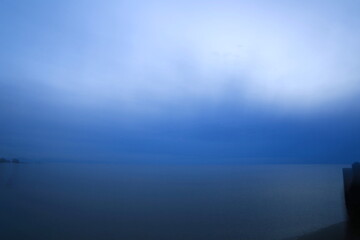 青い夕暮れの海をぼかした背景素材
