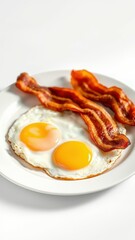 Delicious breakfast with crispy bacon and sunny-side up eggs on a white plate