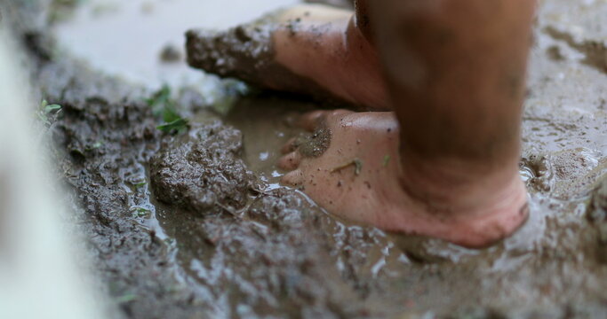 Child foot standing in dirty mud. toddler feet in wet mud