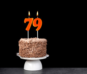 Birthday card with candle number 79 - Chocolate cake on black background.