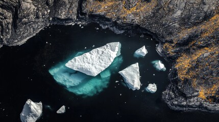 Aerial View of Small Icebergs Floating on Dark Cold Mountain Lake in Norway, Surrounded by Thawing Ice and Golden Pollen