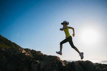 Athletic woman running on sunrise seaside rocks