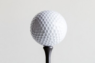Close-up of a white golf ball on a tee against a light gray background.