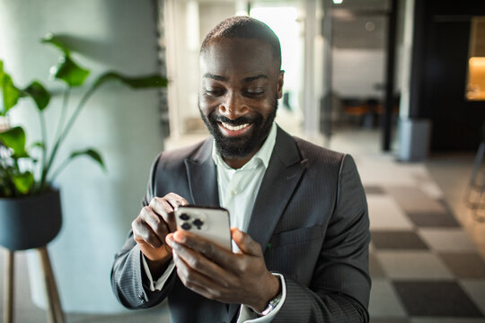 Smiling businessman using smartphone in modern office