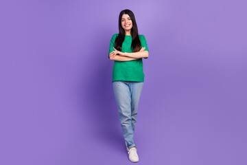 Joyful young woman in casual green t-shirt posing confidently against violet background