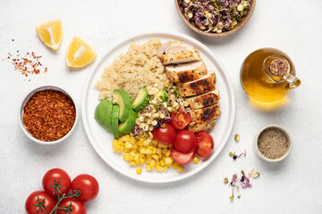 Chicken breast with quinoa, tomatoes, avocado, corn, green sprouts in a plate on a white background top view. Healthy food concept