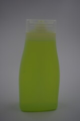 Items, household chemicals, cosmetics, shower gel, shampoo. Matte white bottle with transparent cap with bright, toxic green, yellow liquid gel.