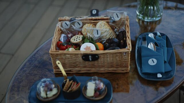 A table with a basket of food and a blue napkin. The basket has a number 1 on it