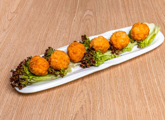 Crispy Golden Flower Balls with lettuce leave served in tray dish isolated on wooden table side view of hong kong food