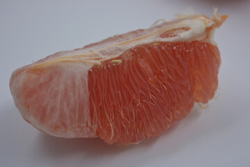 Healthy and wholesome food, beautiful fresh fruits. The red flesh of the grapefruit with large white slices is located on a white plastic background.
