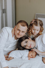 Fototapeta premium A family of four, including a couple and their two children, are posing for a picture with a newborn baby. Scene is warm and loving, as the family is embracing