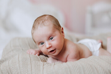 A baby is laying on a blanket with its eyes closed. The baby is smiling and he is content