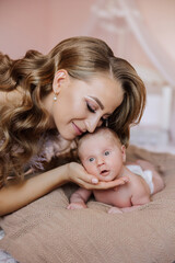 A woman is holding a baby and smiling. The baby is looking at the camera. Scene is warm and loving