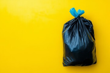A black garbage bag tied with a blue tie on a bright yellow background.