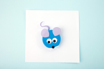 plastic bottle cap lid mouse, DIY project for kids, reuse everyday materials, top view, Minimalist flat lay composition on light blue background. Craft and DIY recycling concept. Design for poster