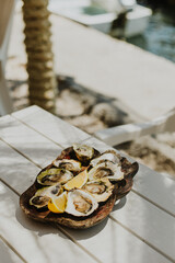 Delicious oysters with lemon on a wooden plate in restaurant by the sea.