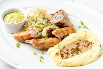 A delicious plate featuring a variety of grilled sausages, creamy mashed potatoes with gravy, fresh coleslaw, and a side of mustard. Perfect for food lovers and restaurant menus.