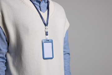Man with blank badge on gray background, closeup. Space for text